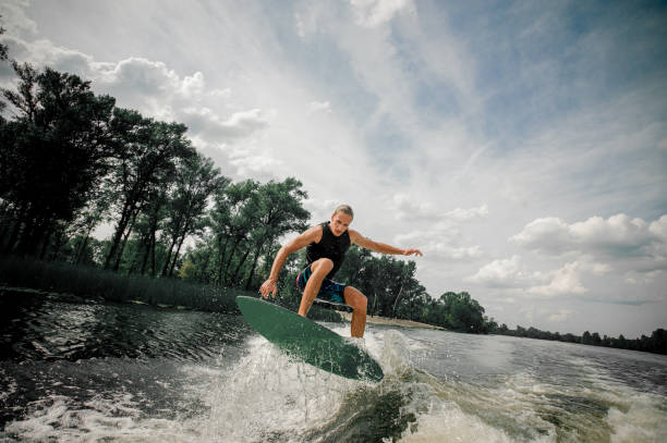 istock Active man wakesurfing on the board down the river 939715714