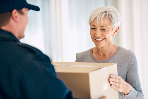 Cropped shot of a senior woman accepting delivery from a male courier at her home