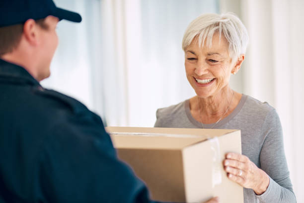 Happy to have it in her hands Cropped shot of a senior woman accepting delivery from a male courier at her home receiving stock pictures, royalty-free photos & images