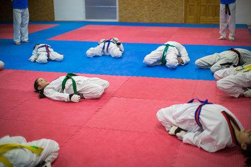 Girls and boys stretching their legs before taekwondo practice