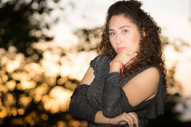 istock Young Lady Outdoors Portrait Sunset Behind Leaning head on Left Hand 939728170