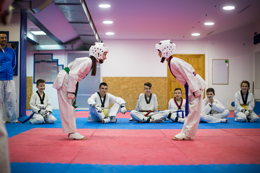 Boy and girl fighting in taekwondo indoors