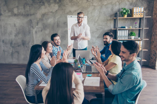 praca gret! udany zespół biznesowy klaska w nowoczesne stacje robocze, świętując wydajność nowego produktu - meeting community manager business zdjęcia i obrazy z banku zdjęć