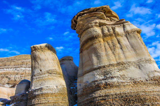 Majestic hoodoos stand tall against a vibrant blue sky, showcasing the unique geological formations of drumheller, a testament to the power of erosion and time