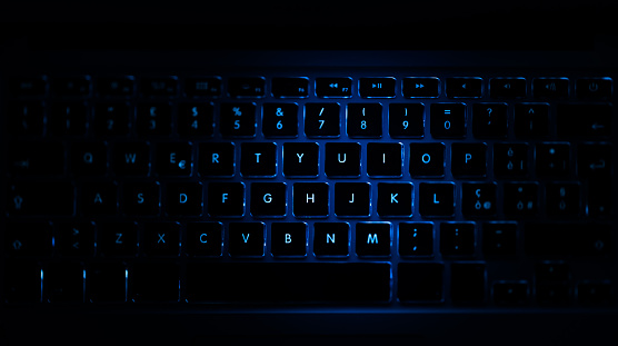 Closeup of laptop keyboard illumination, blue backlit keyboard