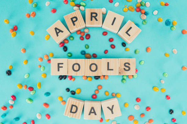 top view of arranged wooden cubes in april fools day lettering on blue surface with candies, 1 april holiday concept top view of arranged wooden cubes in april fools day lettering on blue surface with candies, 1 april holiday concept april fools day stock pictures, royalty-free photos & images