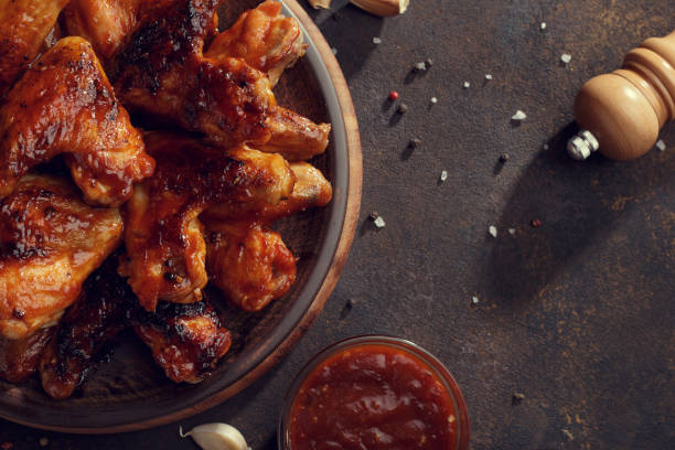 istock Baked chicken wings with bbq sauce on the plate on rusty background. 939746446