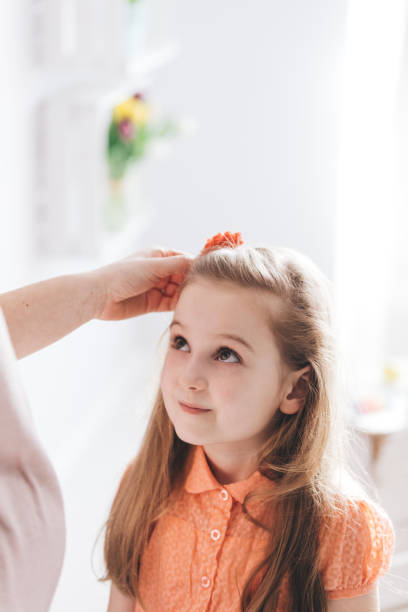 istock Mother fixing her young daughter's hair 939746546