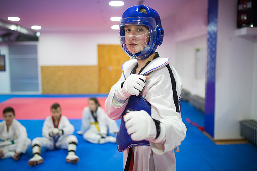 Taekwondo fighter standing with his fists in air, wearing sports helmet