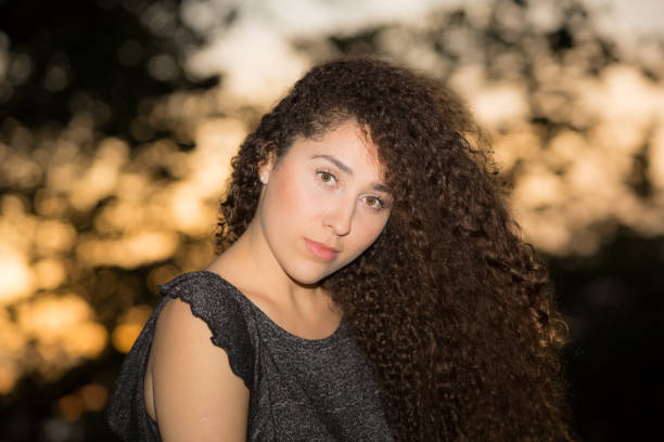 istock Young Lady Outdoors Portrait Sunset Behind Hair on Face 939761600