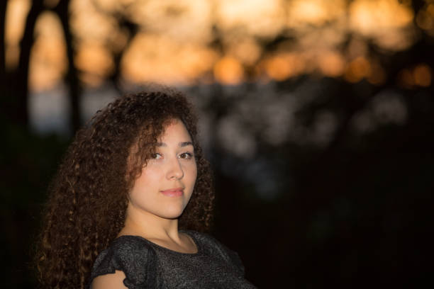 istock Young Lady Outdoors Portrait Sunset Behind Hand of Face 939762322