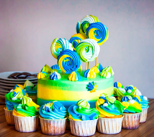 istock Bright colorful cake with cupcakes standing around. 939765710