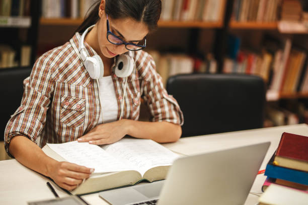 istock Young female student study in the school library.She reading a book. 939771562