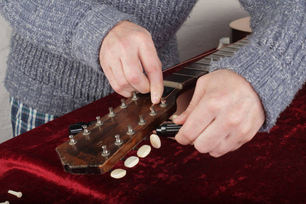 istock Guitar repair and service - Worker fix new strings 939775496