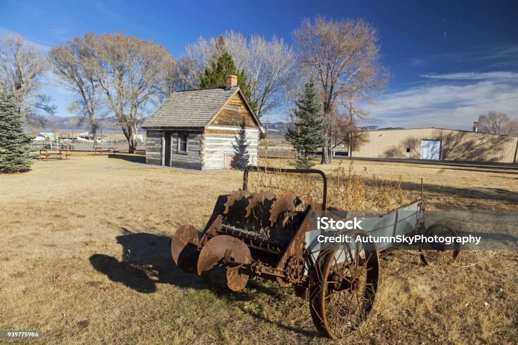 Mormon Pioneer Heritage Park Panguitch Utah Rusted Wagon Wheel in front of old Wild West Log Cabin in Mormon Pioneer Heritage Park, Scenic Highway 89 near City of Panguitch, Utah Utah Stock Photo