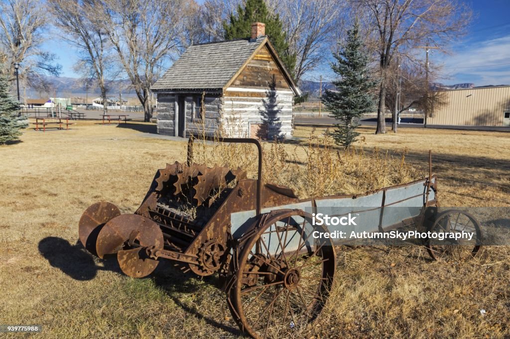 Mormon Pioneer Heritage Park Panguitch Utah Rusted Wagon Wheel in front of old Wild West Log Cabin in Mormon Pioneer Heritage Park, Scenic Highway 89 near City of Panguitch, Utah Mormonism Stock Photo