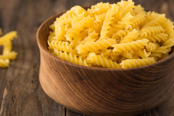 istock Raw pasta in wood plate on wood background 939778754