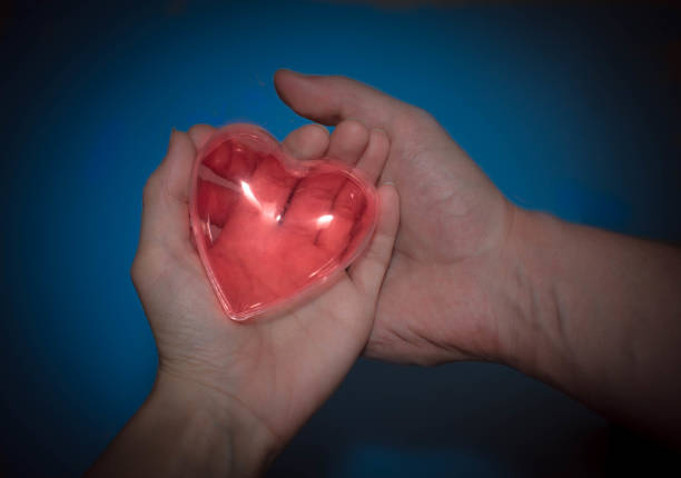 istock red heart in women's and men's hands on blue background 939785648