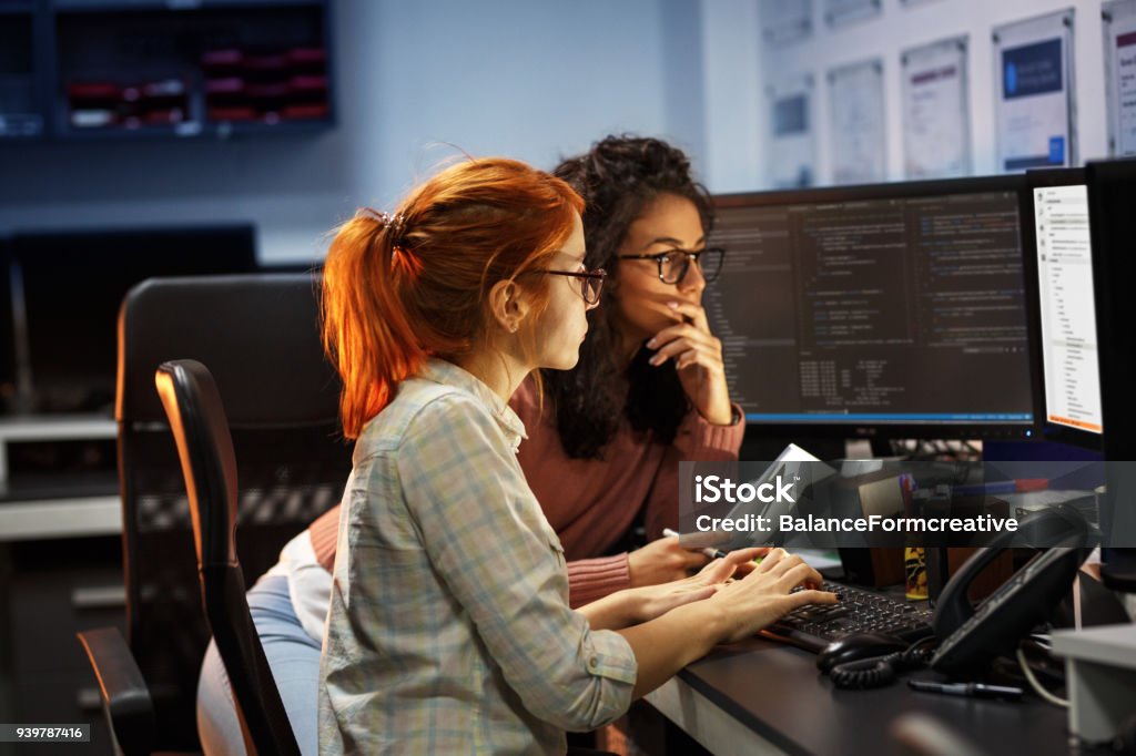 Deux femelles programmeurs travaillant sur nouveau projet. Ils travaillent tard dans la nuit au bureau. - Photo de Technologie libre de droits