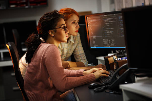 istock Two female programmers working on new project.They working late at night at the office. 939787916