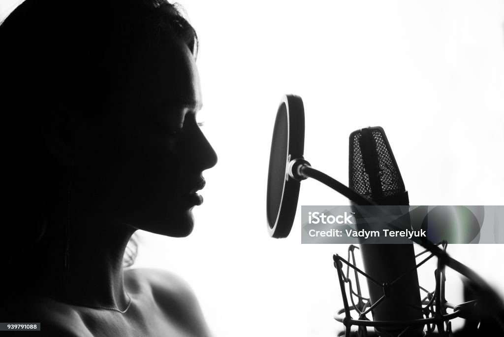 Woman singing in the recording studio. Black and White. Woman singing in the recording studio. Profile of a woman with a beautiful face and lips. Singer Stock Photo