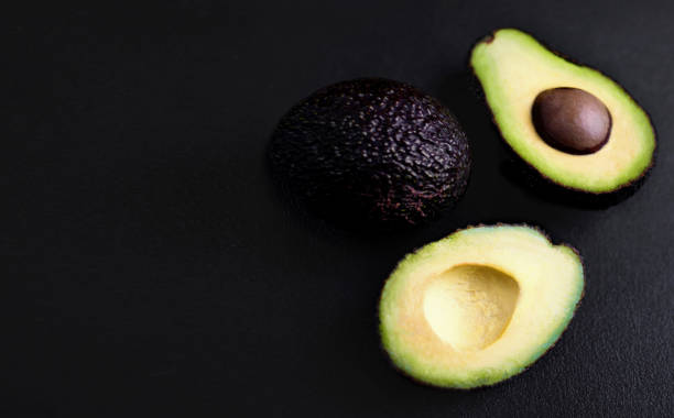 istock Avocado on a black background. Half of avocado close up. Top view. Copy space