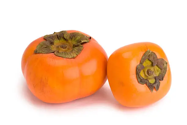 Big and small Fuyu persimmon on white background with clipping path
