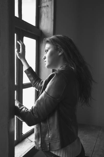 istock Girl standing next to a window. 939807686
