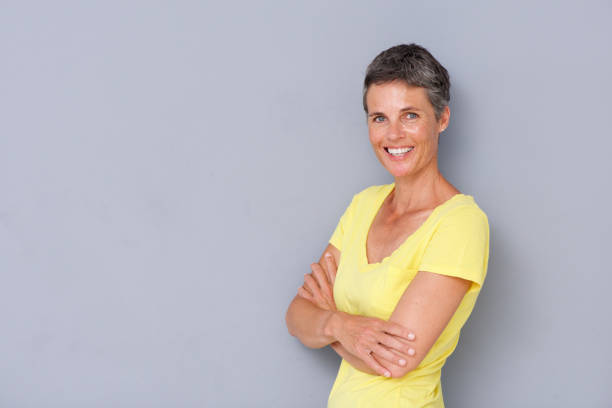 istock beautiful older woman smiling against gray background 939808824