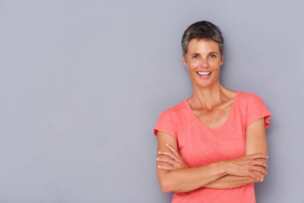 istock smiling older woman against gray wall 939808844