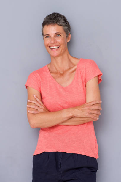 istock relaxed older woman smiling by gray wall 939808846