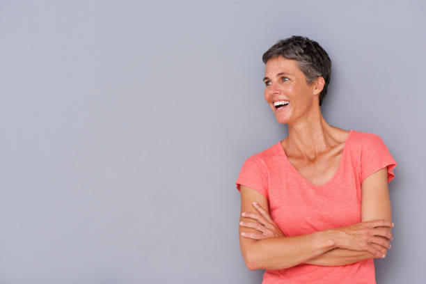 istock laughing older woman against gray wall 939808850