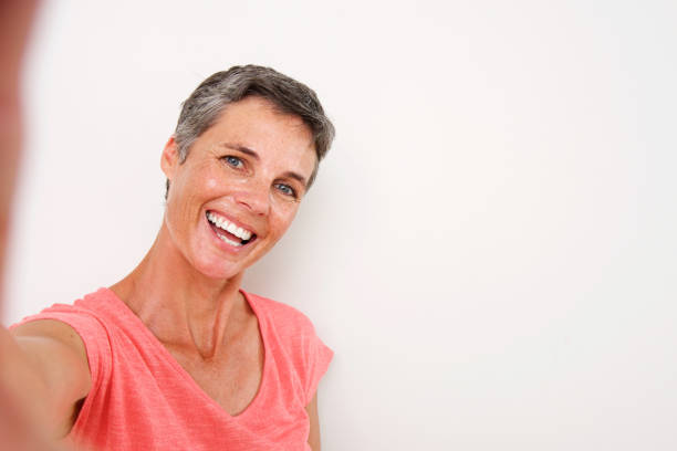 istock attractive middle age woman smiling and taking selfie 939808922