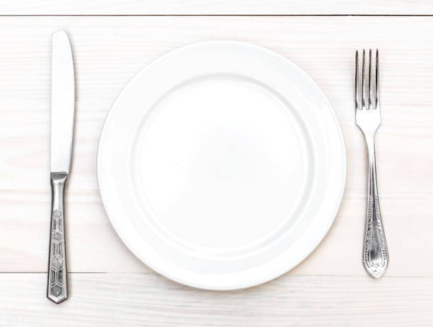 istock Empty dish with fork and knife on the white wooden table. Top view. 939811364