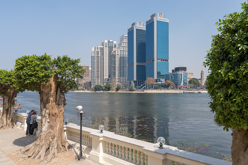 Cairo, Egypt - March 10, 2018: City view from River Nile with overlooking Head Office of National Bank of Egypt and St. Regis hotel with two people looking at the Nile