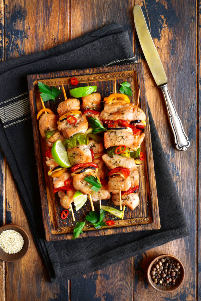 istock Grilled chicken kebab (skewers) with vegetables on a cutting wooden board 939817796