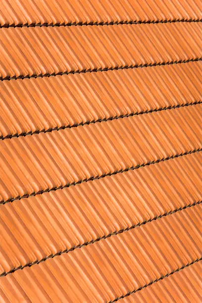 Red orange clay roof tiles in seamless diagonal pattern on sunny day, abstract background texture, architectural details, Adriatic.