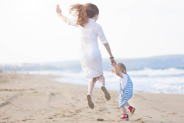 istock Mother and son walking on the beach 939830684