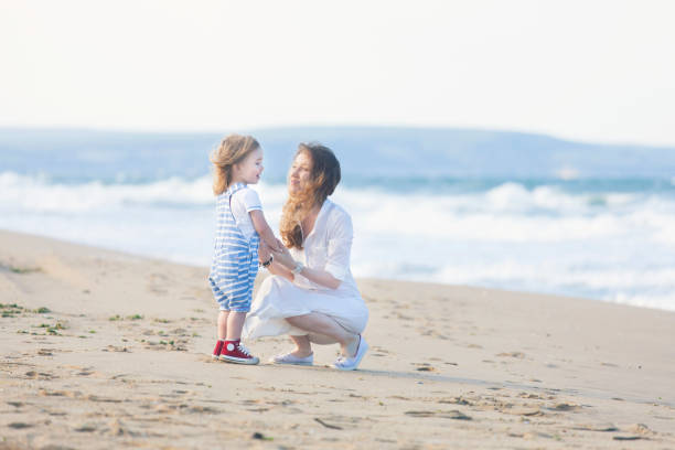 istock Mother and child walking on the beach 939830702
