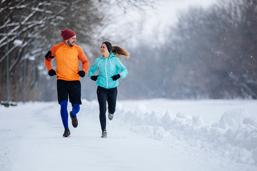 Male and female running outdoors in a beautiful snowy surroundings