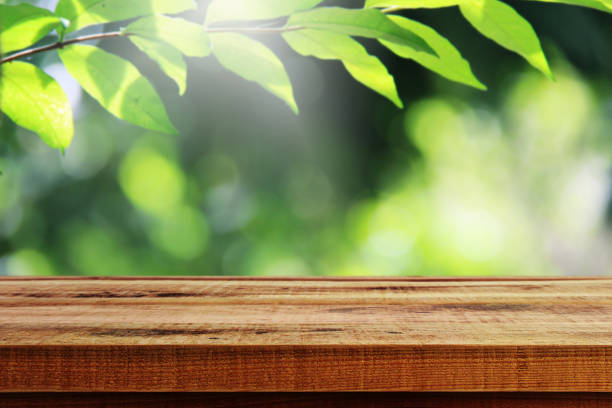 istock Wooden table and green leaf nature background. 939837234