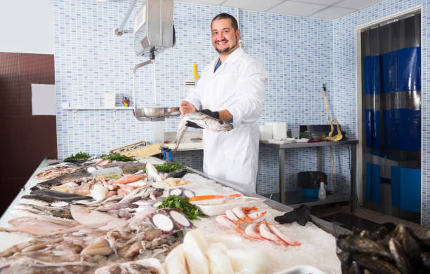 istock Laughing salesman in black glove holding fish 939840550