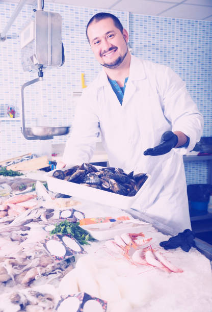 istock Seller holds container of large mussels 939840570