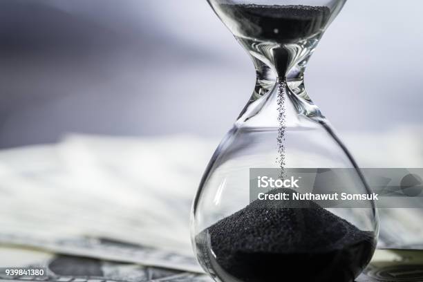 Closed Up Of Sand Falling In Sandglass Or Hourglass On Us Dollar Bills As Time Running Long Term Investment Or Financial Deadline Concept Stock Photo - Download Image Now