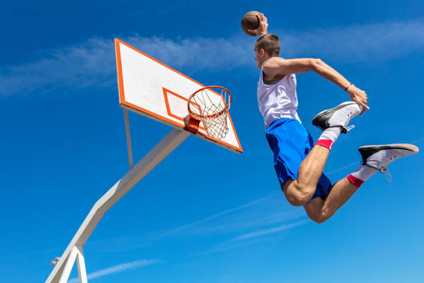 istock Young Basketball street player making slam dunk 939841512