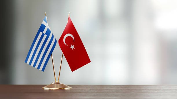 par de la bandera turca y griega en un escritorio sobre fondo defocused - turquia bandera fotografías e imágenes de stock