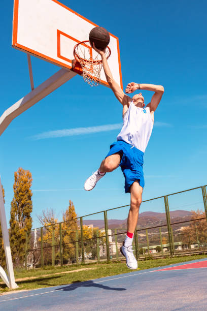 istock Young Basketball street player making slam dunk 939842520