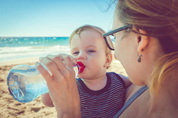 istock Child drinking water on the beach 939848362