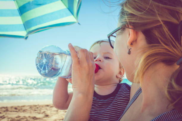 istock Child drinking water on the beach 939848398