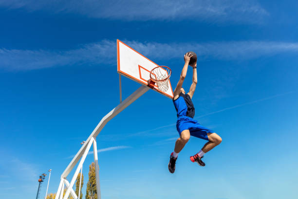 istock Young Basketball street player making slam dunk 939848806